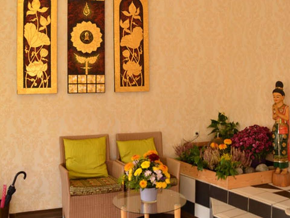 Wartebereich mit Korbsesseln, Blumen und goldenen Lotus-Tafeln bei Chang Thai Massage in Bensheim